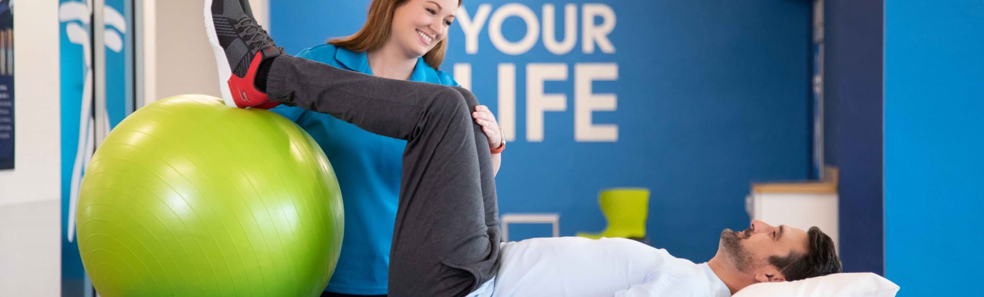 Physical therapist guiding a lower-body exercise with a patient